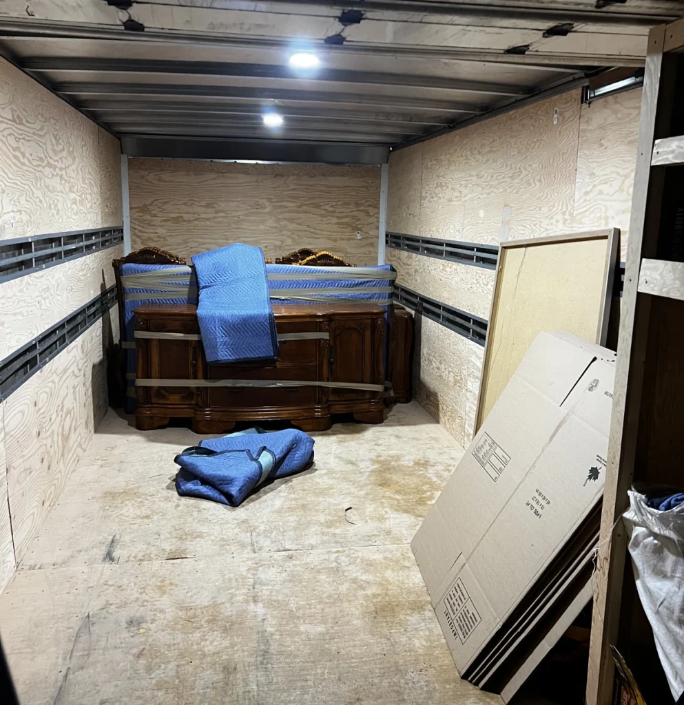 Professional movers loading boxes and protected furniture into a moving truck outside a Mississauga home